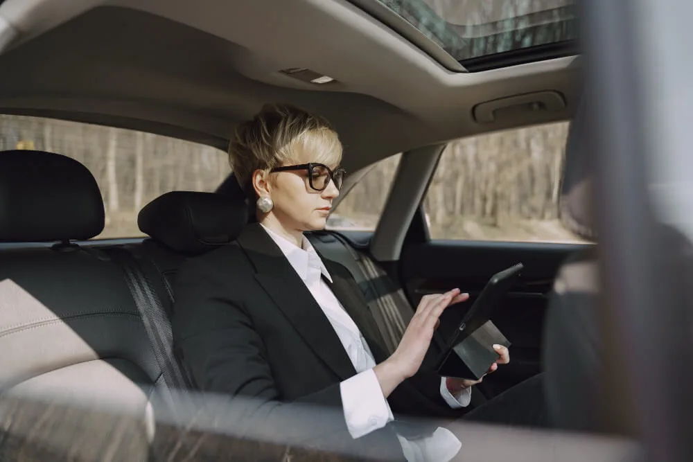 Businesswoman working on her iPad while riding in a black car, representing Galveston limo services and premium executive transportation.